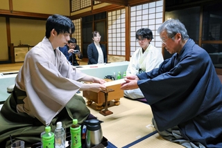 立会人の青野照市九段（右）に封じ手を渡す藤井聡太王位（左）。右から２人目は伊藤匠二冠＝８日午後、神奈川県秦野市、元湯陣屋