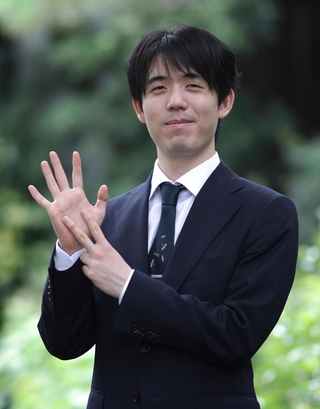 王位戦７連覇にちなんで指を７本示し、記念撮影に応じる藤井聡太王位＝１０日、神奈川県秦野市、元湯陣屋