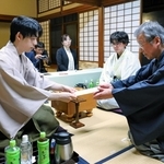 立会人の青野照市九段（右）に封じ手を渡す藤井聡太王位（左）。右から２人目は伊藤匠二冠＝８日午後、神奈川県秦野市、元湯陣屋