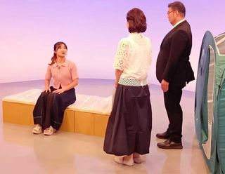 段ボールベッドの座り心地を体験する坂本花織さん（左）ら（サンテレビ提供）