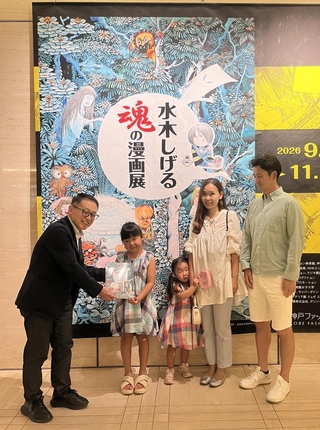 １万人目の入館者となり、記念品を受け取る髙塚凛さんと家族＝９日、神戸ファッション美術館