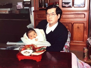 １９８８年、父禎史氏に抱かれる生後３カ月の大村浩一氏（西松屋チェーン提供）