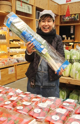 入荷したイチゴを前に北神ねぎを手にする武田愛さん＝神戸市北区大沢町上大沢