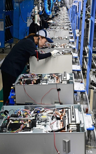 全長１０８メートルのラインで組み上げられる給湯器。手際よい作業が続く＝いずれも明石市二見町南二見、ノーリツ明石本社工場（撮影・斎藤雅志）