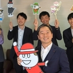 ベビーチーズの公式キャラクターを手にし、社員に囲まれる塚本浩康社長（中央）＝神戸市中央区坂口通１、六甲バター（撮影・小林良多）