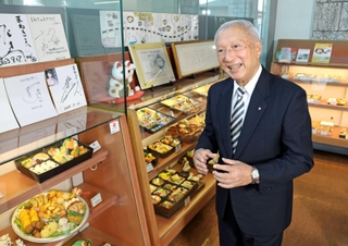 豊富な弁当のサンプルが並ぶ本社で事業の展望を語るまねき食品の竹田佑一会長＝姫路市北条（撮影・小林良多）