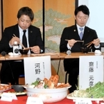 フェアのメニューを試食する兵庫県の斎藤元彦知事（右）とワールド・ワンの河野圭一社長＝神戸市中央区北長狭通２、ひょうご五国ワールド神戸三宮横丁