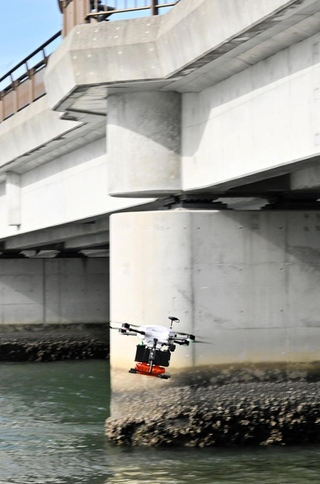 橋の下をくぐって医薬品を運ぶドローン。水面からの高さはわずか１・５メートル＝洲本市塩屋（撮影・内田世紀）