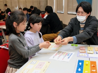 ボードゲームで株式の売買を体験する小学生ら＝神戸市中央区小野浜町