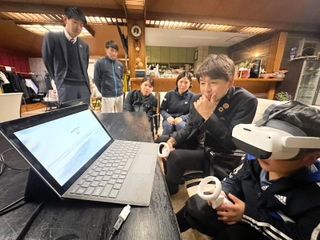 ＶＲ用ゴーグルを着け、能力を測定するゲームに取り組む小学生（右端）とドスカスの落合康ＣＴＯ（右から２人目）＝神戸市垂水区桃山台４、ロイヤルヒルテニスクラブ