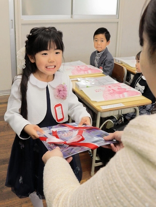 入学祝いとして「神戸タータン」の文具セットを受け取る小学１年生＝神戸市灘区備後町１、成徳小学校
