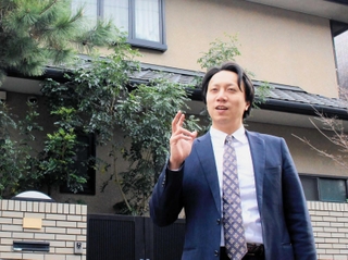 ３月にオープンしたシェアハウスを背に、展望を語る玉井智洋代表＝神戸市灘区高羽町３