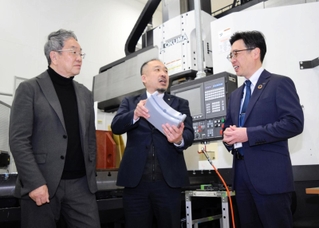 樹脂の精密切削装置の前で、三田電気工業の中村哲哉社長（中央）を囲むひょうご専門人材相談センターの亀井芳郎さん（左）と日新信用金庫の橘宏明さん＝神戸市西区見津が丘５