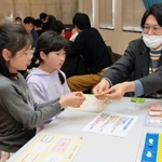 ボードゲームで株式の売買を体験する小学生ら＝神戸市中央区小野浜町