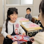 入学祝いとして「神戸タータン」の文具セットを受け取る小学１年生＝神戸市灘区備後町１、成徳小学校