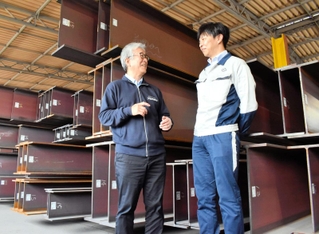 鋼材の前に立つ大和工業の塚本一弘取締役常務執行役員（左）とサステナビリティ経営推進室の駒智之室長＝姫路市大津区勘兵衛町５
