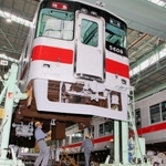 約２メートルの高さに持ち上げられた車体。台車と結合する前に、中心ピンの表面を磨く作業が行われていた＝明石市二見町東二見、山陽電気鉄道東二見車両工場