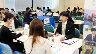 学生に事業内容を説明する企業の担当者（右）＝神戸市中央区東川崎町１、神戸クリスタルホール