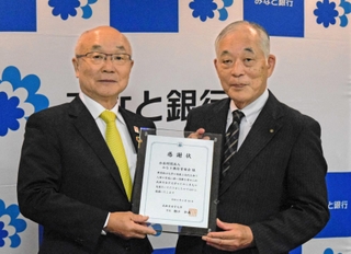 みなと銀行育英会の服部博明理事長（左）に感謝状を手渡す武庫川女子大の瀬口和義学長＝みなと銀行本店