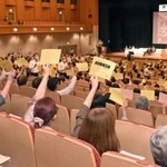 コープこうべ総代会で、採決時に議決書を掲げる総代たち＝神戸市中央区港島中町６、神戸ポートピアホテル