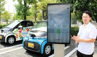 スマートフォンの専用アプリを使った電気自動車の充電サービスについて説明する関西電力の担当者＝神戸市西区竜が岡１