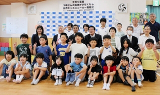 子ども用スニーカーの寄贈式で、記念撮影に臨むヂャームフリーや児童館の関係者らと、菅の台児童館の子どもたち＝神戸市須磨区菅の台４