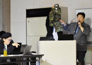 新商品の開発に向けて発表する参加企業の担当者と金谷勉さん（左）＝西宮市西宮浜１、西宮浜産業交流会館