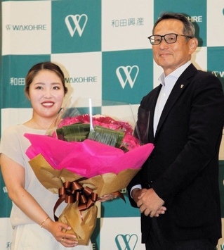 メジャー制覇を祝う花束を、和田興産の溝本俊哉社長（右）から受け取った女子ゴルフの古江彩佳選手＝２２日午前、神戸市中央区栄町通４、同社