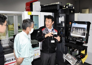 最新モデルのレーザー加工機について来場者に説明する三菱電機の社員（中央）＝尼崎市長洲西通１、同社西日本メカトロソリューションセンター