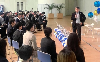 アシックスの内定式で、富永満之社長（右端）のあいさつを聞く内定者たち＝神戸市中央区港島中町７、同社