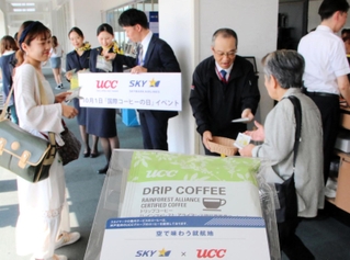 「国際コーヒーの日」を記念して、搭乗客にドリップコーヒーを手渡すＵＣＣグループとスカイマークの関係者＝神戸空港