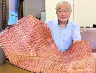 銅メッキを施した炭素繊維の織物を手にする富士加飾の杉野守彦社長。「リサイクル品は性能が落ちるという概念を覆す製品になる」＝小野市万勝寺町