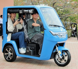 納車されたＥＶトゥクトゥクに試乗する学生ら＝神戸市北区鈴蘭台北町７、神戸親和大