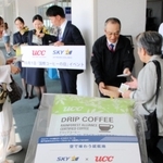 「国際コーヒーの日」を記念して、搭乗客にドリップコーヒーを手渡すＵＣＣグループとスカイマークの関係者＝神戸空港