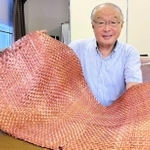 銅メッキを施した炭素繊維の織物を手にする富士加飾の杉野守彦社長。「リサイクル品は性能が落ちるという概念を覆す製品になる」＝小野市万勝寺町