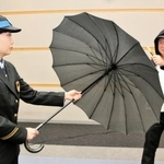 防刃傘を広げ、刃物を持った暴漢役と向き合う乗務員役の女性社員。傘の生地から相手が透けて見える＝１７日午後、大阪市北区、ＪＲ西日本本社