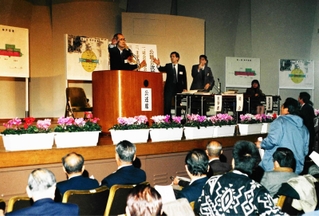 神戸空港の公聴会で壇上に立つ牧冬彦神戸商工会議所会頭＝１９９６年１２月１９日、神戸市中央区、西山記念会館（当時）