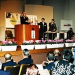 神戸空港の公聴会で壇上に立つ牧冬彦神戸商工会議所会頭＝１９９６年１２月１９日、神戸市中央区、西山記念会館（当時）