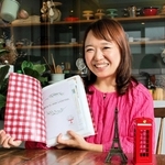 分厚い旅のしおりを手に「お節介の塊」と笑う岡田奈穂子社長。表紙の柄やしおりのデザインはフェリシモ時代の同期が手がけたという＝西宮市大井手町、Ｔａｂｌｅ　ａ　Ｃｌｏｔｈ