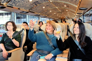 瀬戸内周遊ツアーの出発前、「ゆいプリマ　オリビア」の車内で乾杯するイタリアからの招待客ら＝姫路市南駅前町