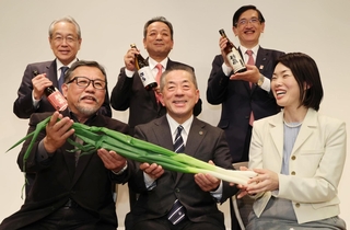 朝来市の岩津ねぎを手にする「ふるさとの光」の選定者３人（前列）。藤岡勇朝来市長（後列中央）らも地元の日本酒をアピールした＝１２日午後、神戸市中央区北野町４、神戸倶楽部（撮影・笠原次郎）