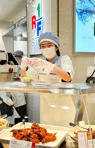 ロック・フィールドの総菜店で販売員として働くみなと銀行から出向中の木下慧さん（同社提供）