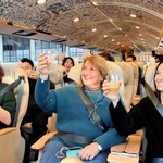 瀬戸内周遊ツアーの出発前、「ゆいプリマ　オリビア」の車内で乾杯するイタリアからの招待客ら＝姫路市南駅前町