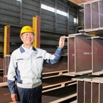 出荷を待つ主力製品のＨ形鋼。自慢の鋼材に触れる大和工業の小林幹生社長＝姫路市大津区勘兵衛町５