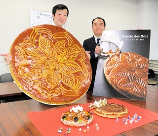 特大の「ガレット・デ・ロワ」を持ち、催しをＰＲする兵庫県洋菓子協会の栗原栄徳副会長（左）ら＝神戸市中央区港島中町６