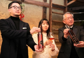 日本酒「現外」を手にする（左から）クリアの生駒龍史代表取締役、神戸大の奥田百合子さん、沢の鶴の西向賞雄取締役＝神戸市東灘区御影本町４