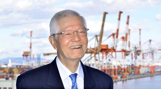 コンテナターミナルを背に、神戸港の未来を語る日本港運協会の久保昌三会長＝神戸市中央区港島９