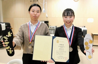 歩きながら充電ができる靴「あるくモバ充」を考案した明石高専の斉藤美音さん（右）と北畑美羽さん＝明石市魚住町西岡
