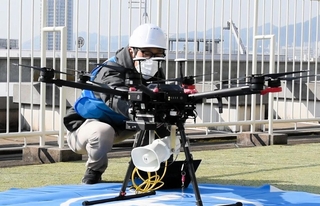 神戸国際会館の屋上でスピーカーを搭載したドローンの準備をする担当者＝神戸市中央区御幸通８