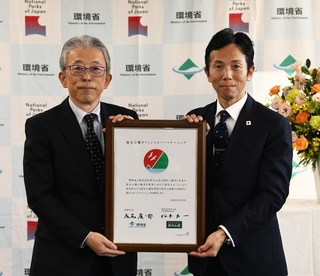 締結書を手にする好日山荘の松本良一社長（右）と、環境省の植田明浩自然環境局長＝東京・霞が関（好日山荘提供）